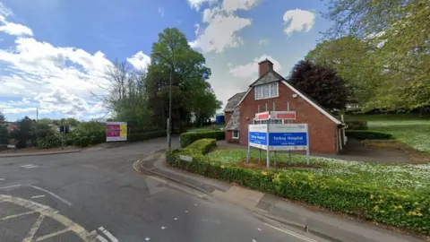 The entrance to Torbay Hospital which is marked with a blue rectangular sign that reads: "Torbay Hospital." 