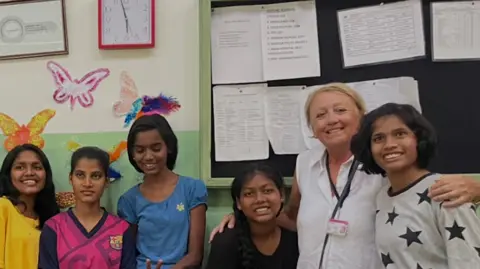 Pat Kellett is standing with a group of young women in India
