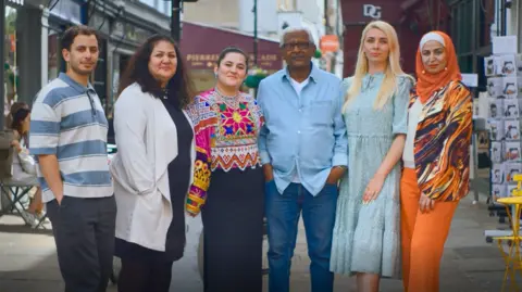 Six people stand and look at the camera - two men and four women.