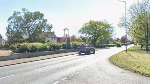 Junction of Station Road with A47 at Little Fransham. Cars are driving along the A47 heading east. 