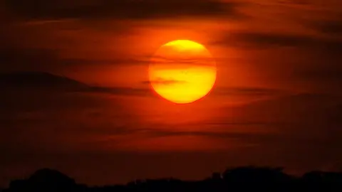Yen Milne A yellow sun with red sky all around it and streaks of black clouds across the scene.