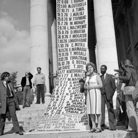 Getty Images  British Labour MP Joan Lestor attends a memorial service for Steve Biko at St-Martin-in-the-Fields, Trafalgar Square, London, to mark the anniversary of the Anti-Apartheid activist's death in detention in South Africa. Draped from the church is a list of 50 other prisoners known to have died in South African detention