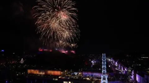 PA Media Fireworks light up the dark sky next to Edinburgh Castle