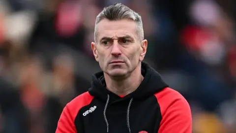 Getty Images Rory Gallagher, with grey hair, wearing red and black sporting top.