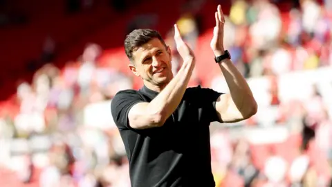 Portsmouth manager John Mousinho smiles as he applauds the fans at full time 