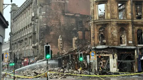 A building devastated by fire, with rubble lying on the street 