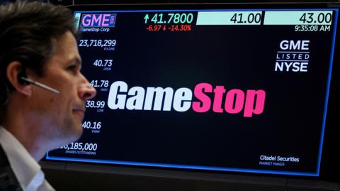 A trader works as a screen displays the trading information for GameStop on the floor at the New York Stock Exchange (NYSE) in New York City, U.S., May 15, 2024.