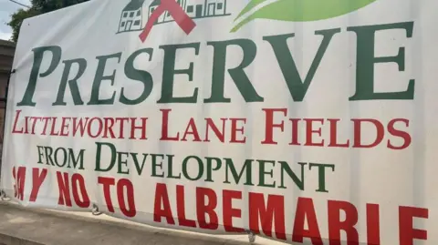 LDRS A white banner with green and red writing which reads 'Preserve Littleworth Lane Fields From Development: Say No To Albemarle'