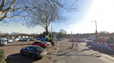 Google Ram Meadow car park's entrance in Bury St Edmunds. Tens of cars are parked with the site.