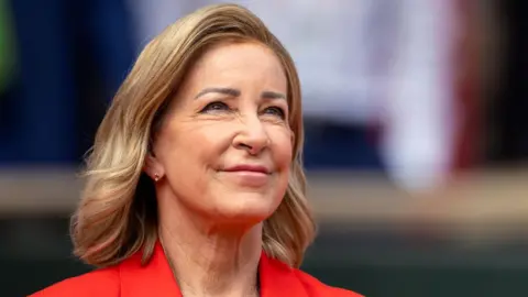 Close up of Chris Evert wearing a red jacket and staring slightly up to the sky 