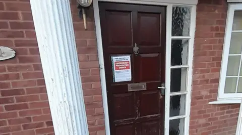 Tamworth Borough Council The front door of a house, with glass panelled windows on the right hand side and a notice on white paper with a red section that reads "emergency prohibition order".