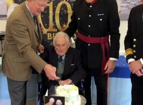 Veteran cutting cake with other army members standing close by