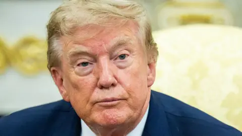 Getty Images Donald Trump in a navy suit with a yellow background.