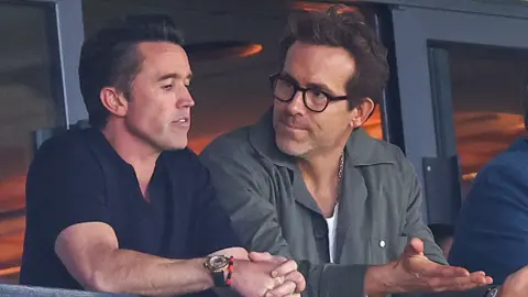 Rob Mac and Ryan Reynolds in discussion in the directors' box at Wrexham