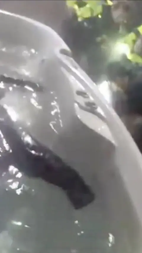 Police in corner of frame arresting a man while black clothing floats in hot tub in the rest of the frame.