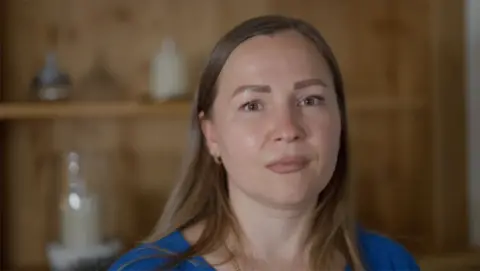 BBC Marina Perederii with agelong  consecutive  brownish  hair, wearing a bluish  top