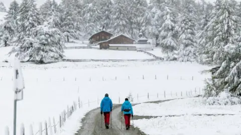 JOHANN GRODER/APA/EXPA/AFP Wandelaars lopen door een besneeuwd landschap in het Kalser Ködnitztal in Kals am Grossglockner, Tirol, Oostenrijk, op 13 september 2024.