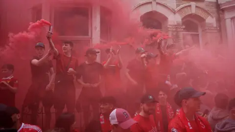 Reuters mist of red from flares let off by a row of young fans standing in front of houses near the stadium