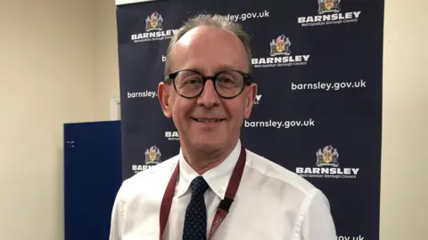 Council leader Sir Steve Houghton - a white man with short grey hair and round black glasses