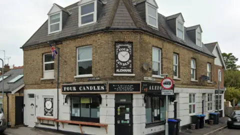Google The Four Candles Alehouse micropub on 1 Sowell St, Broadstairs, Kent. One side of the sign says 'Four Candles' while the other says 'Alehouse'.