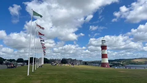 The view from the Hoe in Plymouth with a variety of flags on the left of the picture and Smeaton's Tower with its distictive red and white hoops on the right.