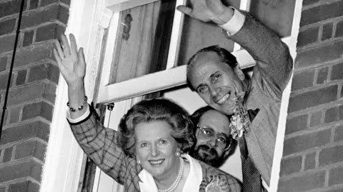PA Media Prime Minister Margaret Thatcher and Norman Tebbit wave to the crowds down below from a window.