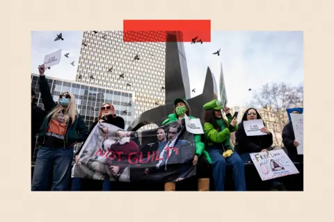 Reuters Women holding a large canvas photograph of Luigi Mangione with 'NOT GUILTY' printed across it. Some are wearing sunglasses, some are dressed as Luigi from the Super Mario Nintendo games.