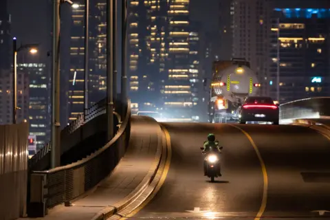 AFP A delivery driver rides on a bridge in Palm Jumeira, in the Gulf Emirate of Dubai on October 7, 2025. 