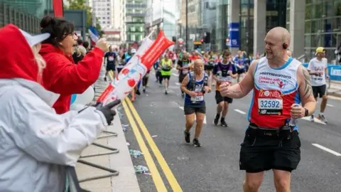 Chris Johnson Chris Johnson in the London Marathon. He is clenching his fist in acknowledgement at a supporter who is cheering him on.