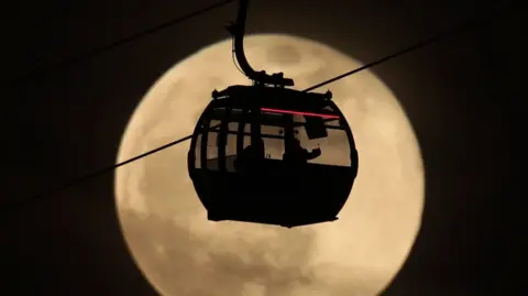 A cable car cabin in front of a full moon