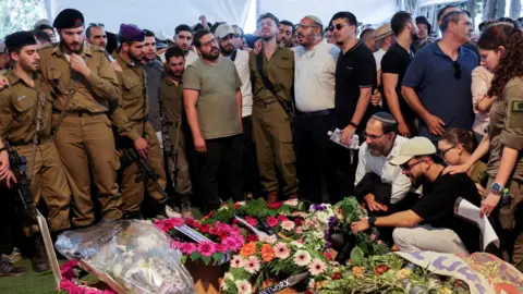 Reuters Mensen rouwen bij de begrafenis van de Israëlische soldaat Sergeant First Class Yakir Shmuel Tatelbaum, die omkwam tijdens de gevechten in Gaza, op de militaire begraafplaats Mount Herzl in Jeruzalem (30 juni 2024).