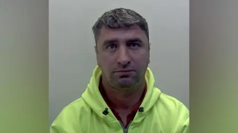 NCA A man with short hair wearing a neon yellow hoodie in a police mugshot.