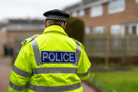 Alphotographic The backmost  of a constabulary  officer, successful  a high-visibility neon yellowish  overgarment   with the connection     constabulary  connected  the back, is shown