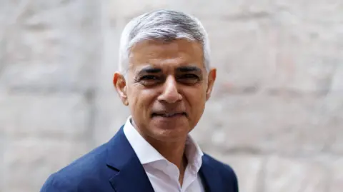 Image of Sadiq Khan, a man with short grey hair, in a blue suit and white shirt