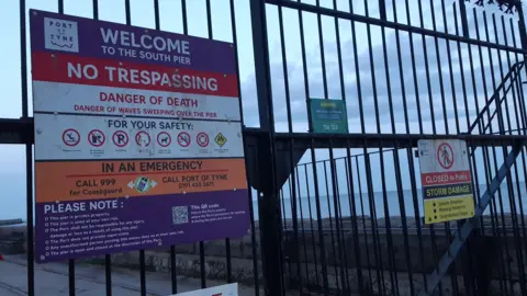 LDRS A close up of the gates which has a purple, red, white and orange sign which says: "Welcome to the South Pier, no trespassing," alongside other safety information.