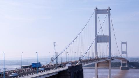 An image showing the Severn Bridge from a distance, with blurred cars passing