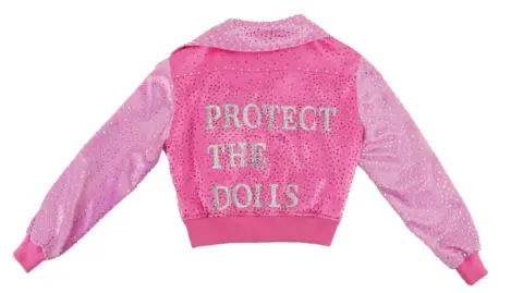 GLAAD A pink jacket. On the back of it is written: Protect the Dolls.