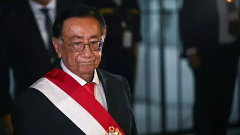 Getty Images Peru's new interim President José María Balcázar wearing a black blazer, red tie, and a sash of Peru's flag.