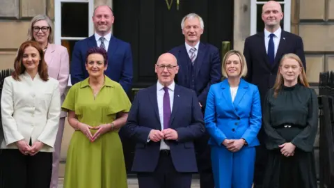Getty Images New Scottish government ministers line up for a photograph outside a stone building 