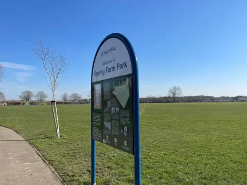 A public park and sign with landfill hill in the background