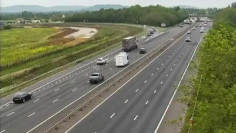 A screenshot taken from a traffic camera showing cars driving along the M5 approaching Tewkesbury.