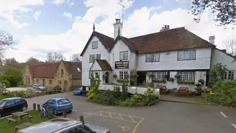 Google A 16th Century pub. There are cars parked outside the white building.