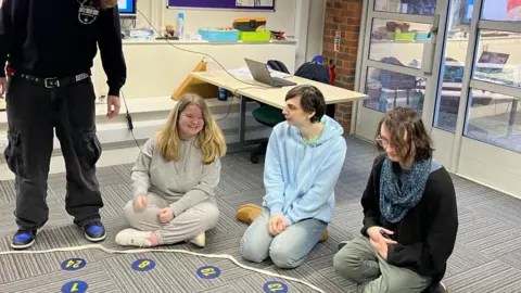 Three young people sat on the floor partaking in a group activity run by Young Gloucestershire and The King's Trust.
