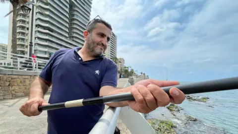 Ayman Sakr holds a fishing rod at the waterfront in Beirut, Lebanon.