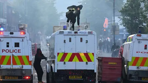 Getty Images A man on top of police Land Rover