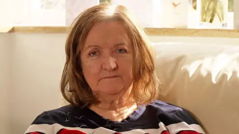 BBC Janet Walters sitting on her sofa with light coming in through the window behind her