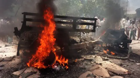 AFP The battered remains of a jeep are on fire and smoking in the middle of the road.