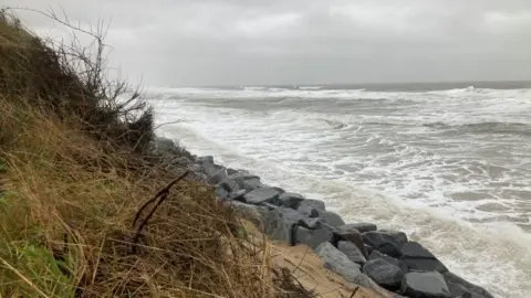 Cliff edge with granite rock defences, with the sea swell against those rocks