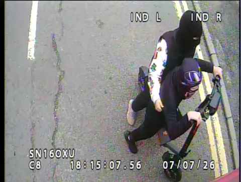 Borders Buses CCTV image of two people on an electric scooter. They have their heads and faces covered and are wearing mostly black clothing