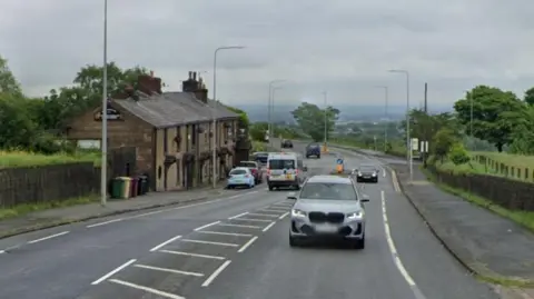 Google Car driving along Chorley Old Road, which is lined by trees, green fields and an old terrace of buildings